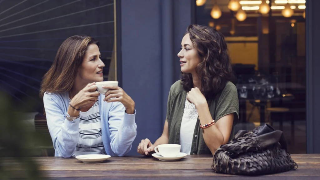 Deux femmes assises à une terrasse de café discutant autour d’un café, représentant une scène typique pour évaluer le test de Bechdel-Wallace.