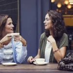 Deux femmes assises à une terrasse de café discutant autour d’un café, représentant une scène typique pour évaluer le test de Bechdel-Wallace.